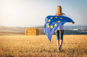 Woman running with waving european union flag in countryside